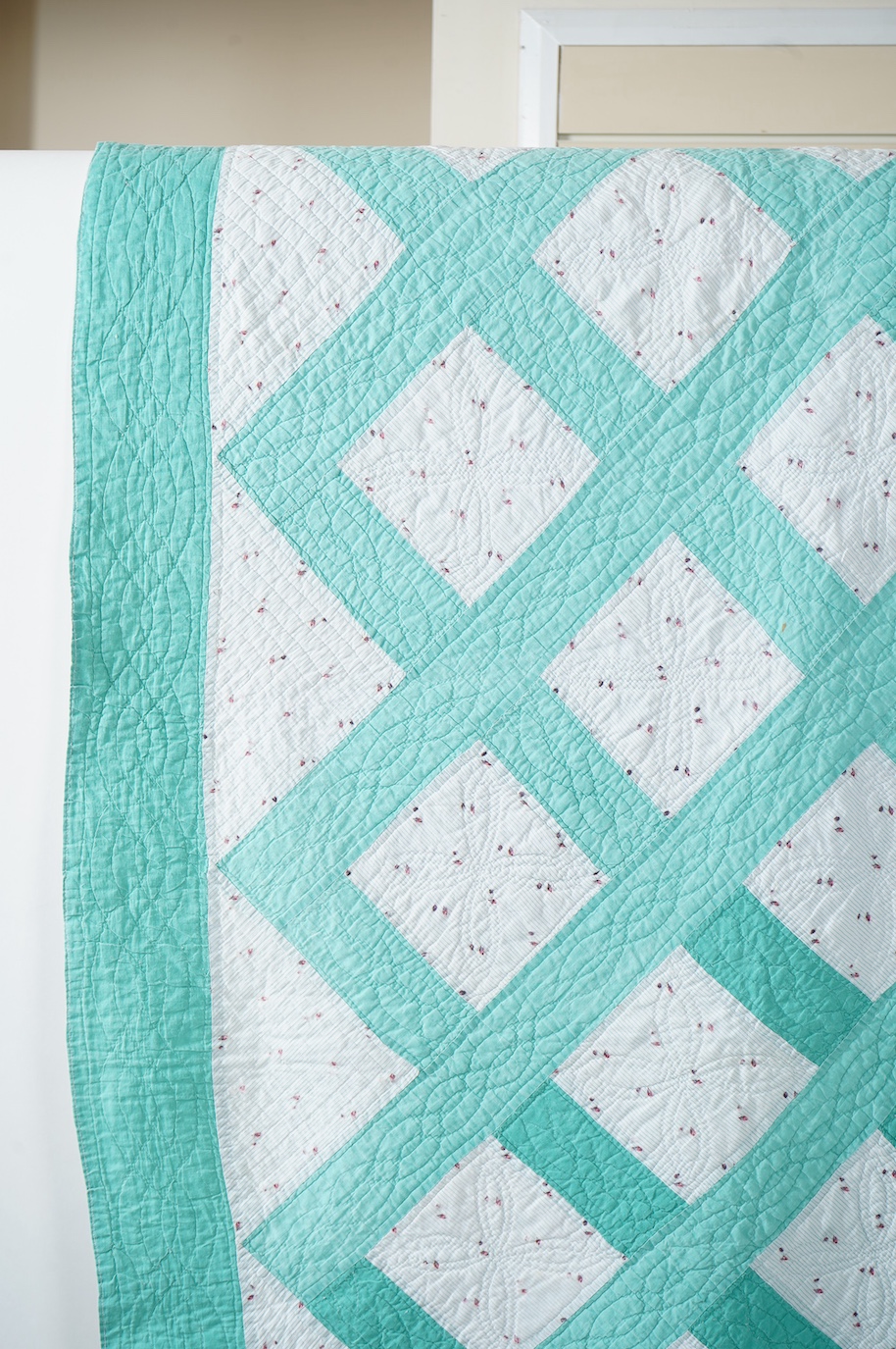 A late 19th early 20th century English, Durham, immaculately hand quilted bedcover. Designed using a plain mint green cotton and a complimentary light floral cotton stripe, in an all over lattice design, with a mint gree